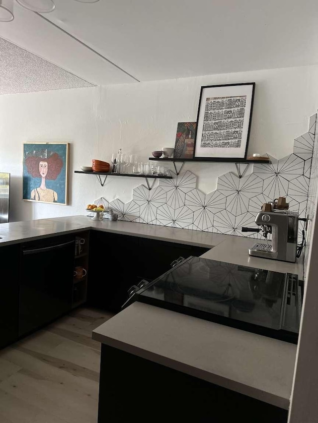 kitchen with a textured ceiling, black appliances, and light wood-type flooring