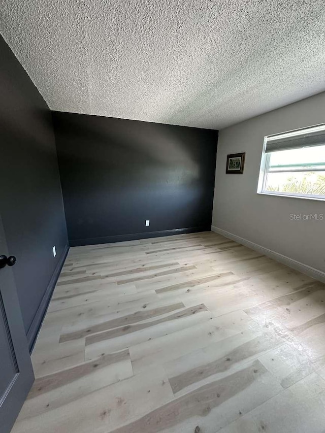 unfurnished room featuring a textured ceiling and light hardwood / wood-style flooring