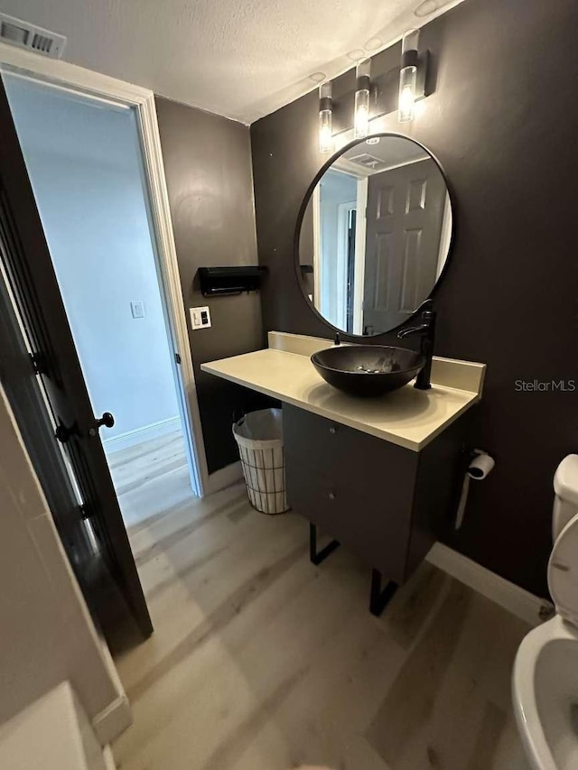 bathroom with wood-type flooring, toilet, a textured ceiling, and vanity