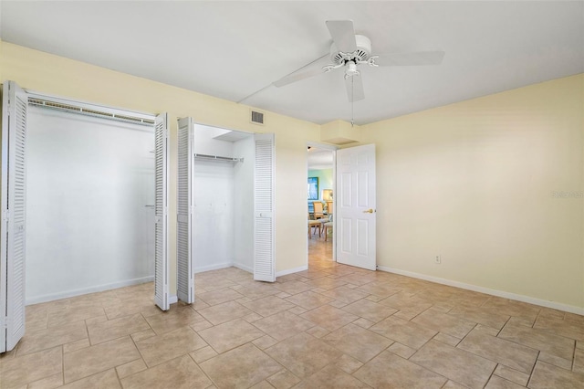 unfurnished bedroom with two closets and ceiling fan