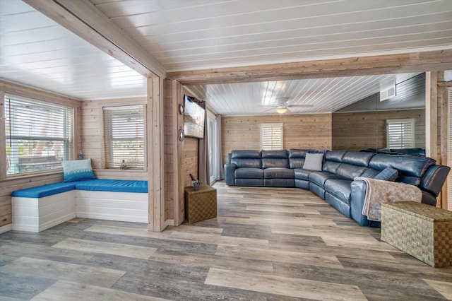 living room featuring ceiling fan, wooden walls, and light hardwood / wood-style flooring