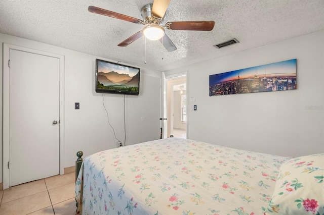 bedroom with a textured ceiling, ceiling fan, and light tile patterned flooring