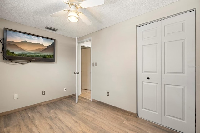 unfurnished bedroom with a closet, ceiling fan, light hardwood / wood-style floors, and a textured ceiling