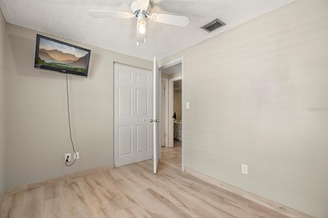 unfurnished bedroom featuring a closet, ceiling fan, a textured ceiling, and light hardwood / wood-style flooring