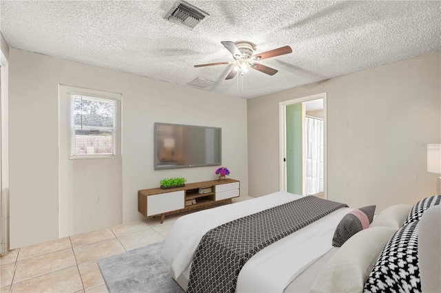 bedroom featuring a textured ceiling, ceiling fan, and light tile patterned floors