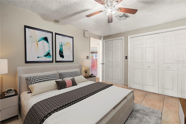 bedroom with a textured ceiling, light tile patterned floors, and ceiling fan