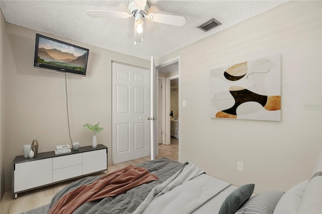 bedroom with a textured ceiling, ceiling fan, a closet, and light hardwood / wood-style floors