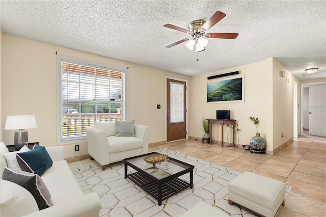 living room with ceiling fan, light tile patterned floors, and a textured ceiling