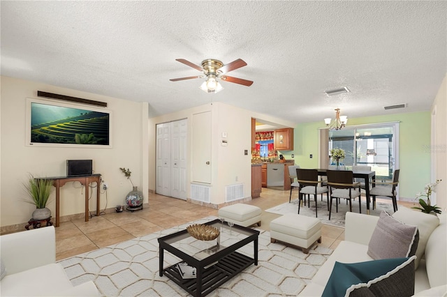 living room featuring a textured ceiling, light tile patterned floors, and ceiling fan with notable chandelier