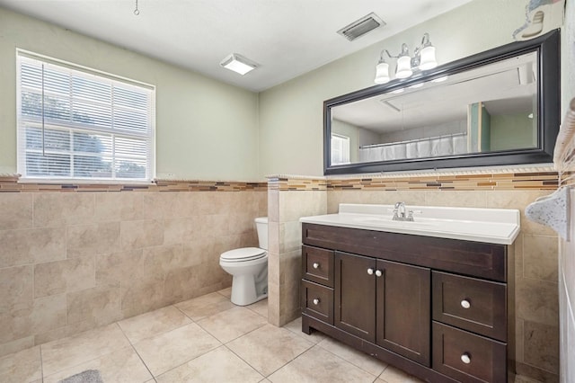 bathroom featuring tile walls, toilet, a wealth of natural light, and vanity