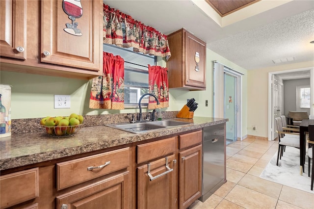 kitchen with light tile patterned floors, dishwasher, a textured ceiling, and sink