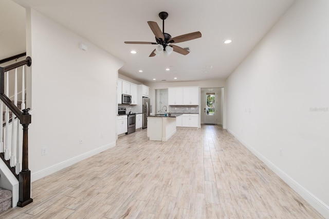 unfurnished living room with ceiling fan, light hardwood / wood-style floors, and sink