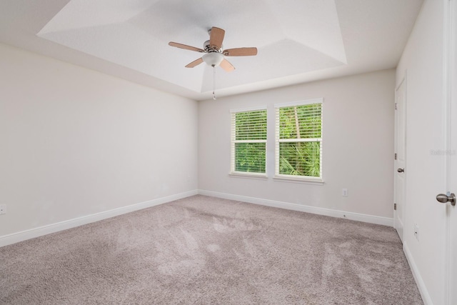 carpeted spare room with ceiling fan and a tray ceiling