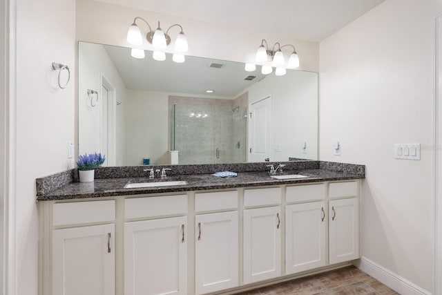 bathroom featuring a shower with shower door and vanity