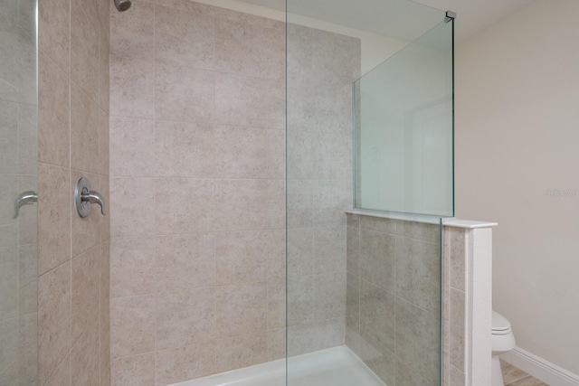 bathroom featuring tiled shower and toilet