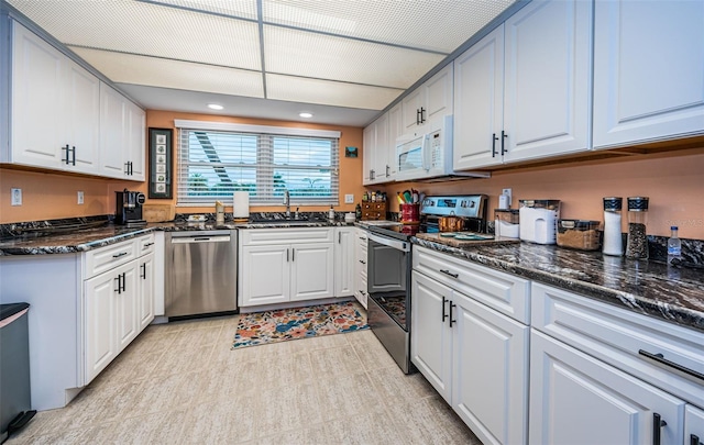 kitchen featuring sink, white cabinetry, stainless steel appliances, and dark stone countertops