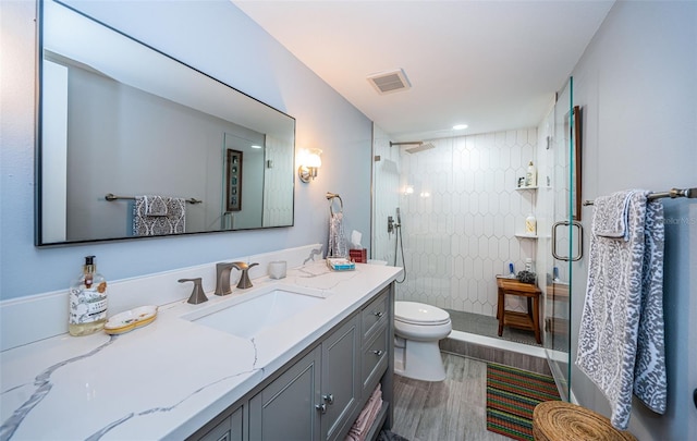 bathroom featuring hardwood / wood-style floors, toilet, walk in shower, and vanity