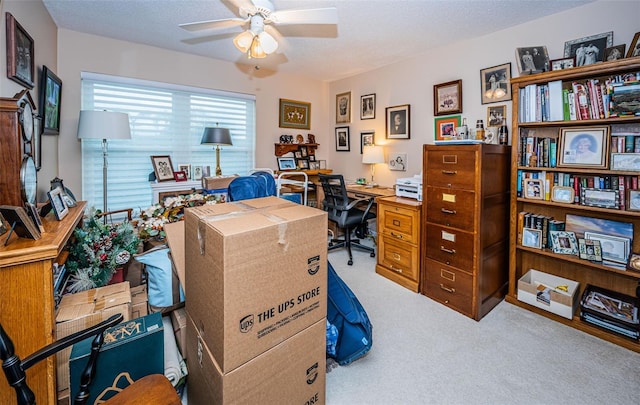 office area with a textured ceiling, ceiling fan, and light colored carpet