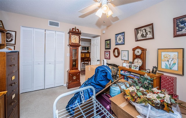 bedroom featuring ceiling fan, light colored carpet, a closet, and a textured ceiling