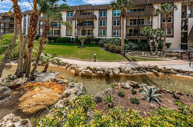 view of home's community with a water view and a yard