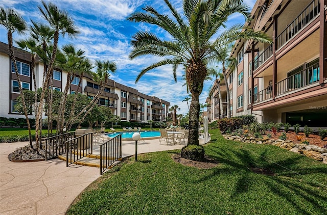 view of community featuring a patio area, a pool, and a yard