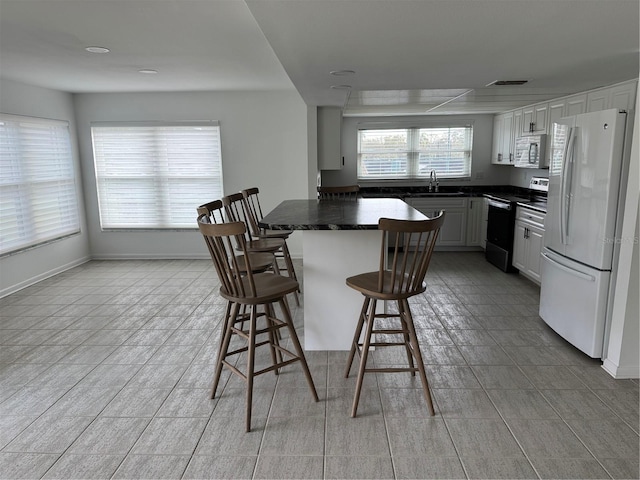 kitchen featuring white cabinetry, sink, white appliances, and a breakfast bar area