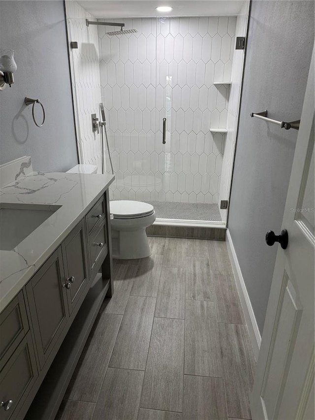 bathroom with toilet, vanity, and tiled shower