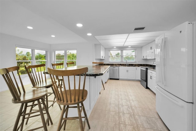 3021 Countryside Blvd Unit 28A, Clearwater, FL 33761 - kitchen with kitchen peninsula, sink, a breakfast bar area, stainless steel appliances, and white cabinets