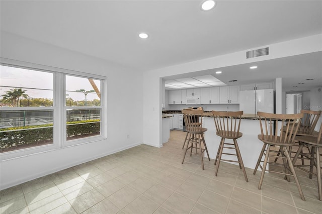 3021 Countryside Blvd Unit 28A, Clearwater, FL 33761 - kitchen with kitchen peninsula, white cabinets, a breakfast bar, and white appliances