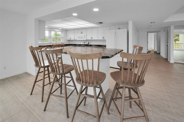 3021 Countryside Blvd Unit 28A, Clearwater, FL 33761 - kitchen featuring a breakfast bar area, light tile patterned floors, white cabinets, and white appliances