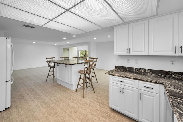 3021 Countryside Blvd Unit 28A, Clearwater, FL 33761 - kitchen with white cabinets, dark stone counters, a kitchen breakfast bar, and white fridge