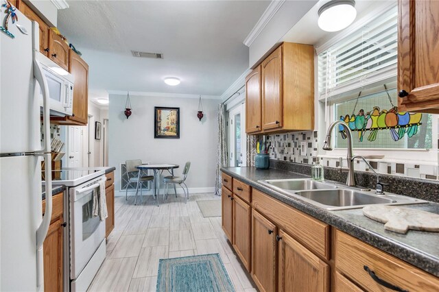 kitchen featuring white appliances, a wealth of natural light, backsplash, and sink