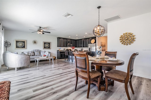 dining room featuring light wood-type flooring and ceiling fan with notable chandelier