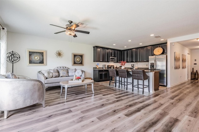 living room with ceiling fan and light wood-type flooring