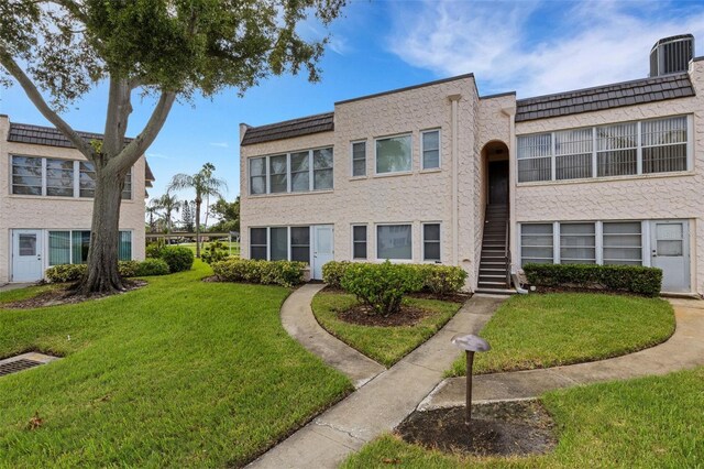 view of property with a front lawn and central AC