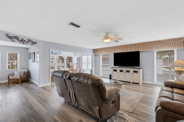 living room featuring a textured ceiling, light hardwood / wood-style flooring, and ceiling fan