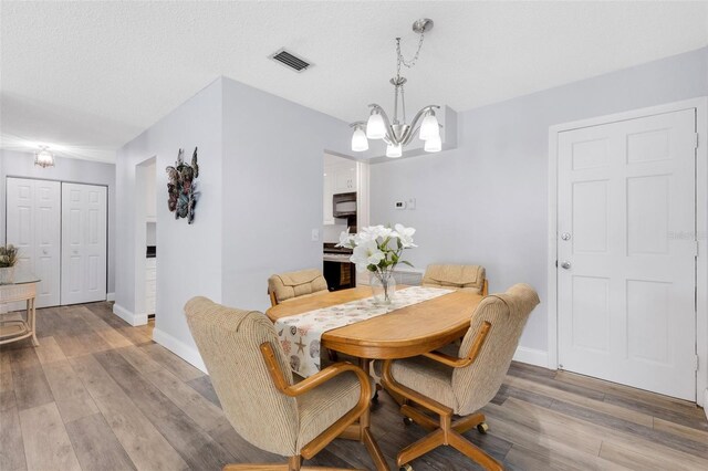 dining space featuring hardwood / wood-style floors, a chandelier, and a textured ceiling