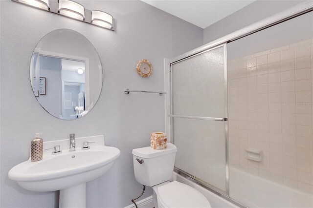 full bathroom featuring shower / bath combination with glass door, toilet, and sink