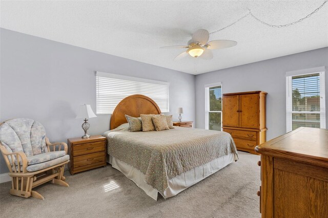 bedroom featuring ceiling fan, light carpet, and a textured ceiling