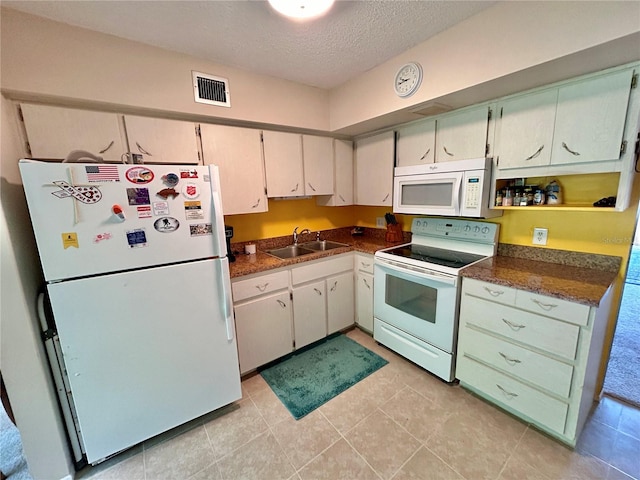 kitchen with white appliances, light tile patterned floors, a textured ceiling, and sink