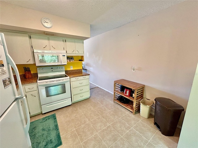 kitchen with white appliances, light tile patterned flooring, and a textured ceiling