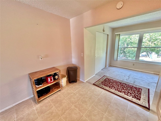 doorway with light tile patterned flooring and a textured ceiling