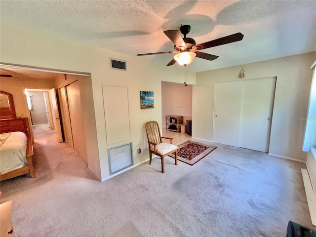 unfurnished room featuring ceiling fan, light carpet, and a textured ceiling