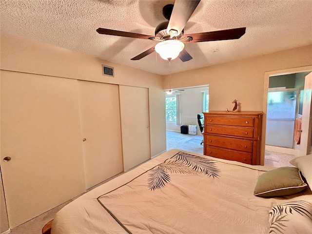 carpeted bedroom featuring a textured ceiling, ceiling fan, and a closet