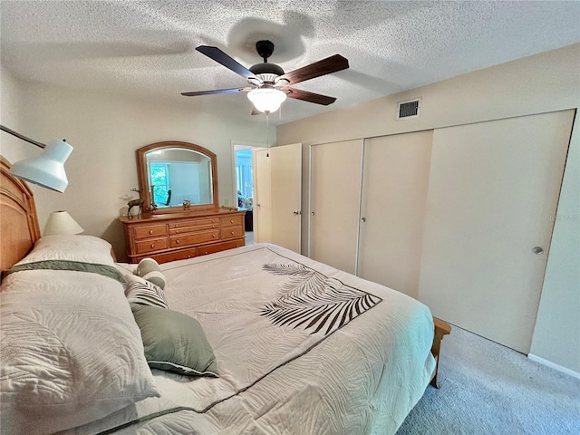 bedroom with a textured ceiling, ceiling fan, and light carpet