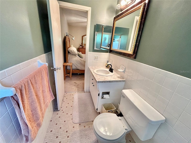 bathroom with toilet, tile patterned flooring, vanity, backsplash, and tile walls