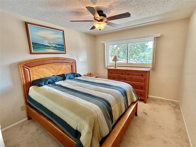 bedroom with ceiling fan, light carpet, and a textured ceiling