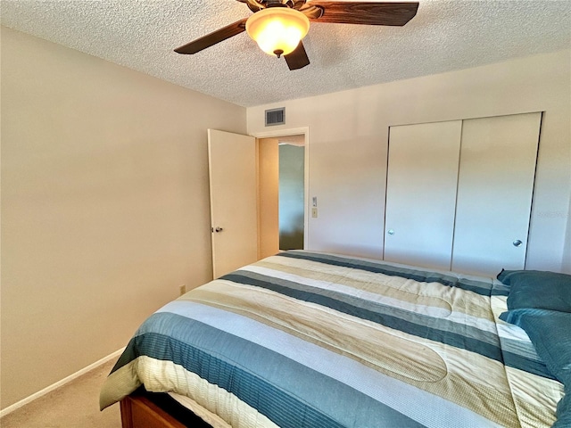 bedroom with a textured ceiling, carpet, ceiling fan, and a closet