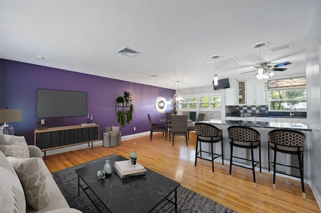 living room with a healthy amount of sunlight, sink, ceiling fan, and light hardwood / wood-style floors