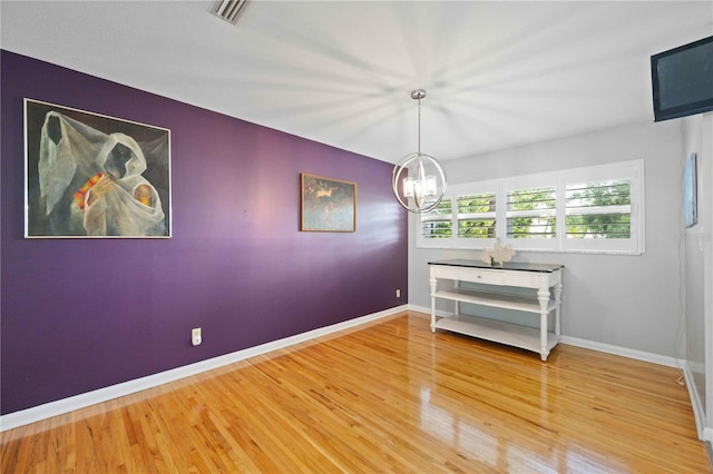 unfurnished dining area with hardwood / wood-style flooring and a notable chandelier